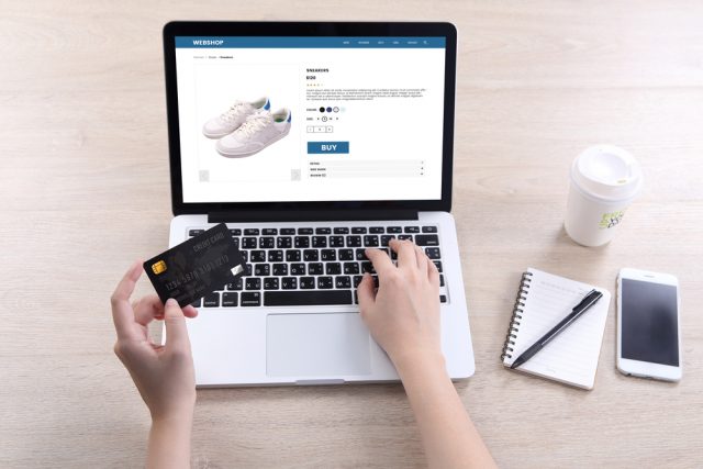 Woman entering bank card details to purchase shoes online